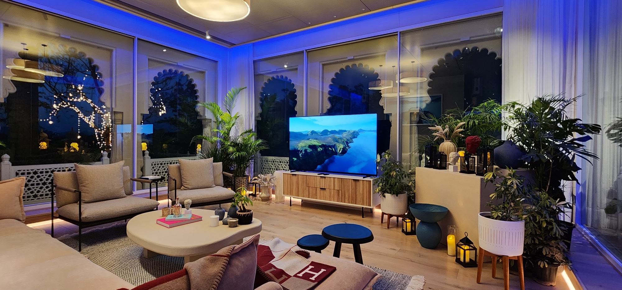 Modern lounge with blue accent lighting and indoor plants at night