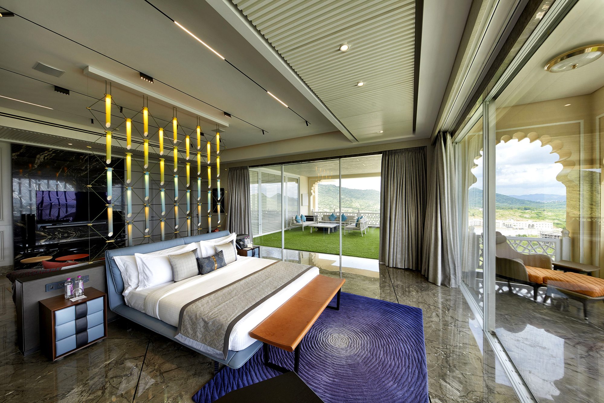 Hotel suite bedroom with hill views and pendant lighting