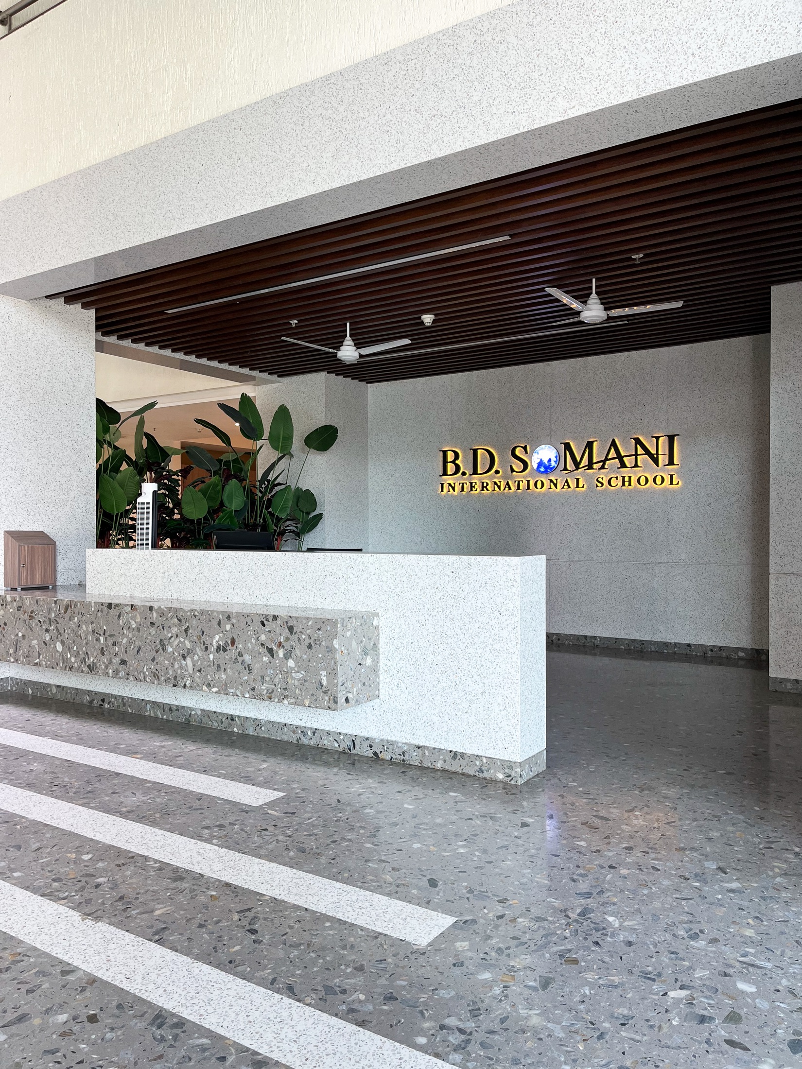 School reception desk in terrazzo with backlit signage