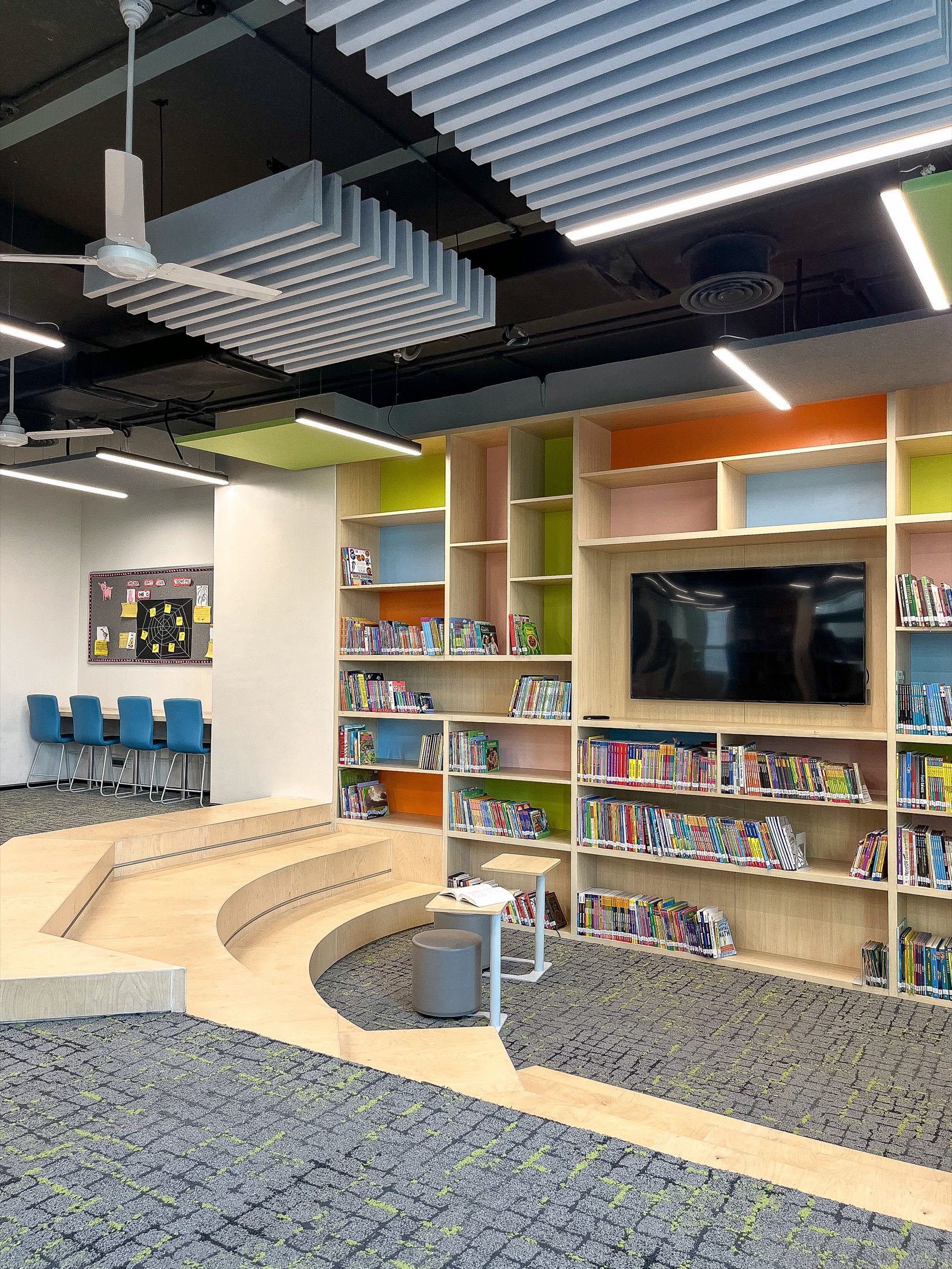 Tiered wooden amphitheatre reading nook surrounded by bookshelves
