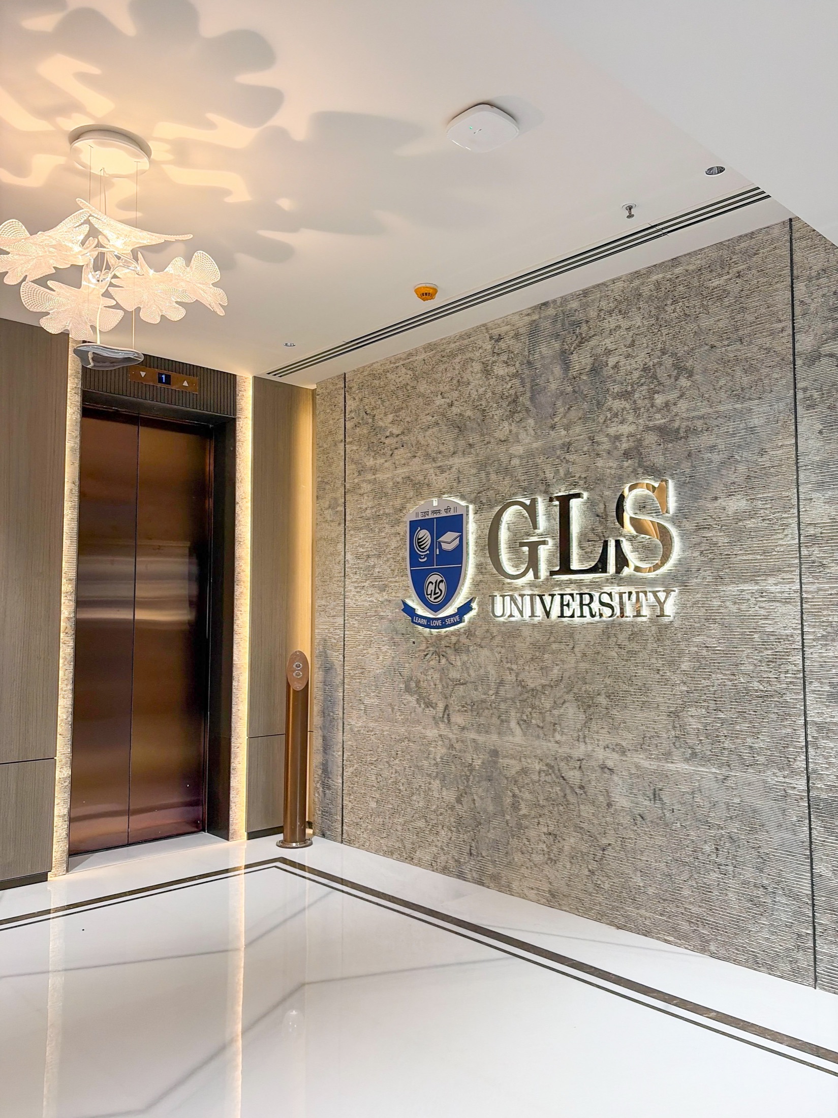 University lobby with backlit stone wall and crystal chandelier