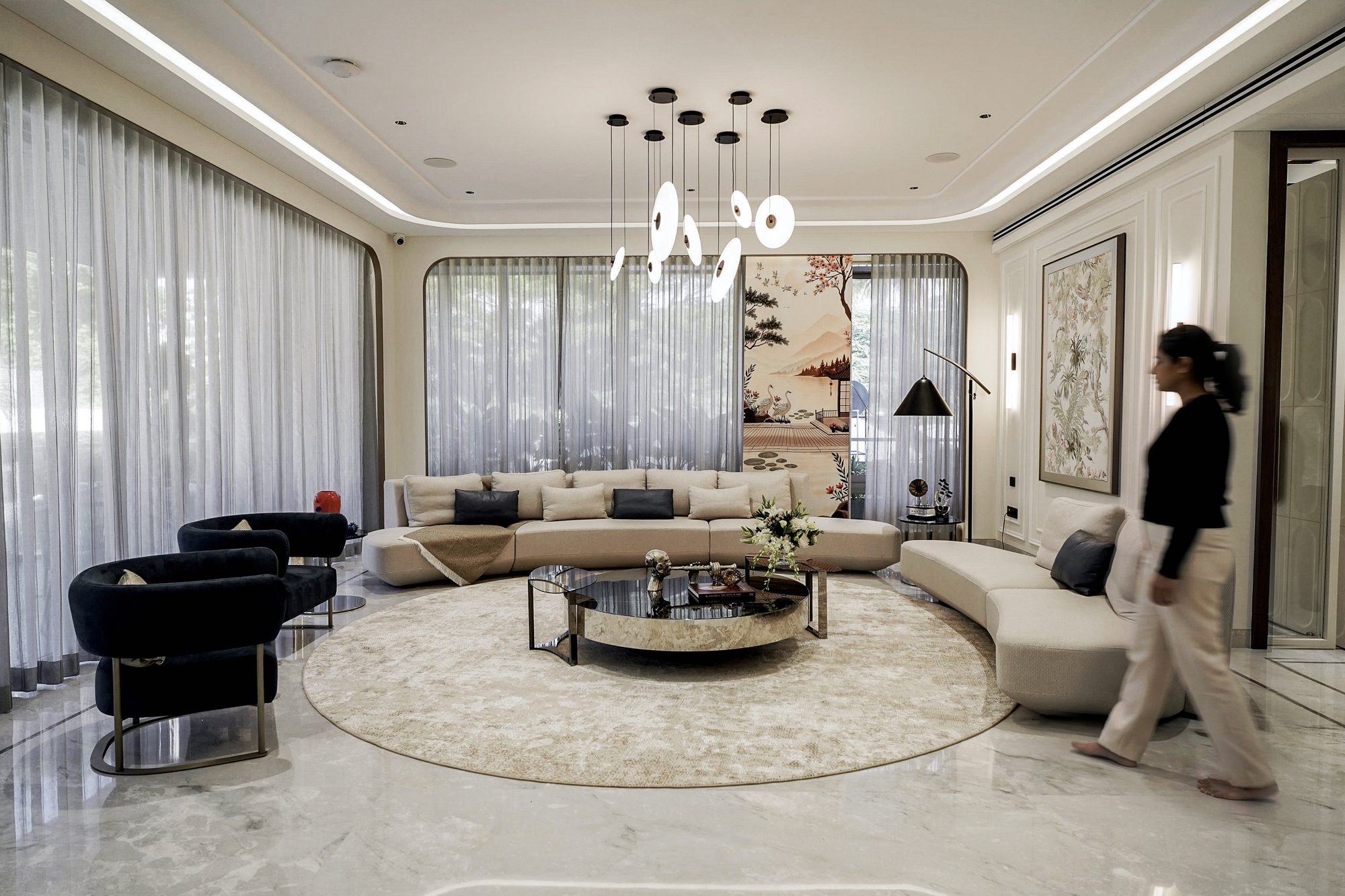 Living room with curved sofas around a round rug and brass coffee table